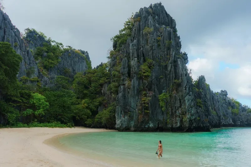 Scenic view of Hidden Beach in El Nido, Palawan, featuring white sand, turquoise water, and dramatic limestone rock formations.