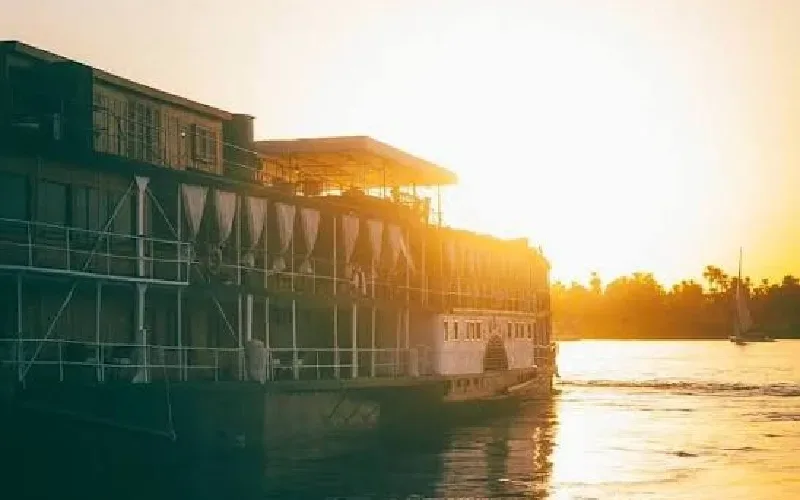 Bateau de croisière naviguant sur le Nil au coucher du soleil près d’Assouan