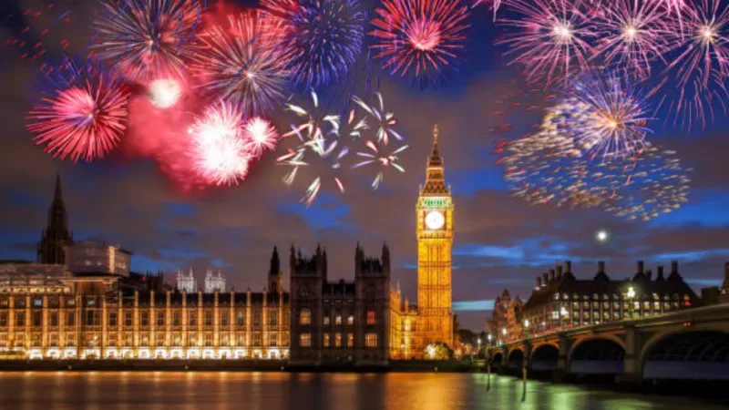 Buntes Feuerwerk über dem Big Ben in London, England, zur Feier des New Year's Eve, mit funkelnden Lichtern, die die berühmte Uhr und die Skyline der Stadt erhellen.