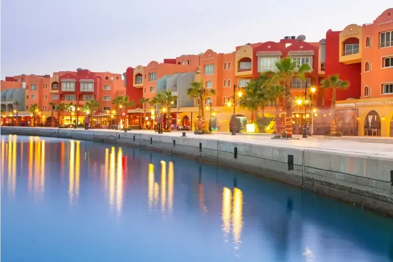 Il lungomare della Marina di Hurghada, in Egitto, con i suoi edifici colorati illuminati dalle calde sfumature del tramonto.