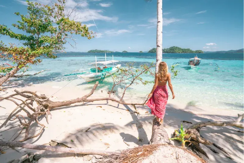 Tropical beach in the Philippines with clear turquoise water and a traveler