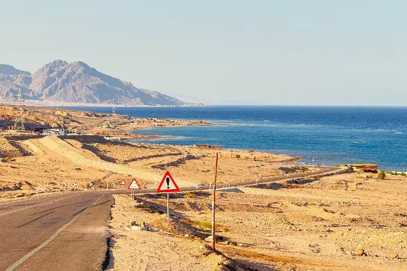 Wüstenküstenstraße entlang des Meeres mit Bergen und Warnschildern in Ägypten