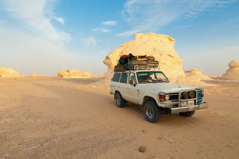 Toyota Land Cruiser in der Weißen Wüste Ägyptens vor beeindruckenden Kalksteinformationen
