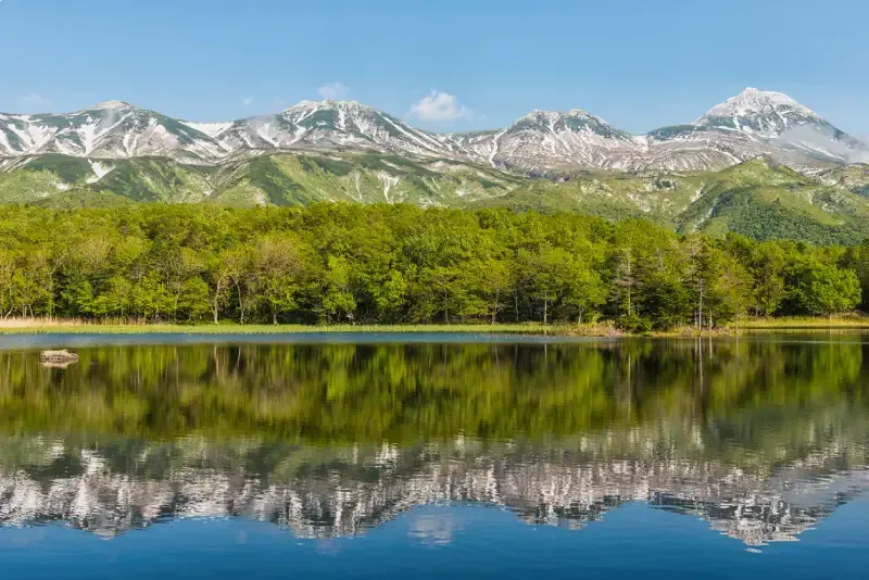 lago-refletindo-montanhas-nevadas-de-shiretoko-e-floresta-verde-hokkaido-japao