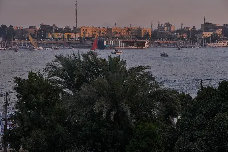 Sonnenuntergang in Luxor, Ägypten, vom Westufer mit Blick über den Nil auf das Winter Palace Hotel am Ostufer