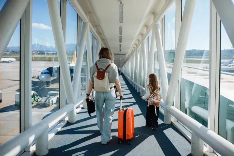 Frau mit kleinem Mädchen und Koffern am Flughafen – Familienreise und Urlaubsvorbereitung