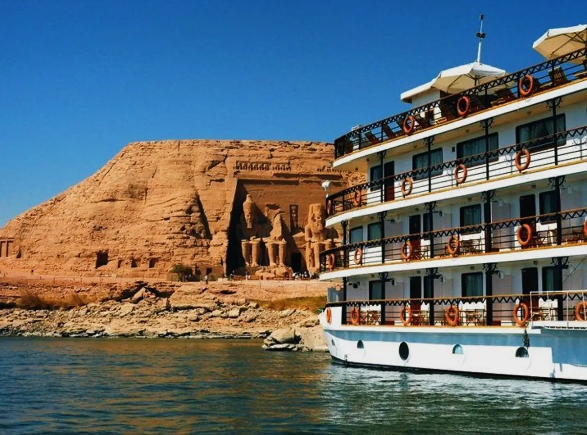 View of a Nile cruise boat sailing near the Abu Simbel Temple on the banks of Lake Nasser in southern Egypt under a clear blue sky