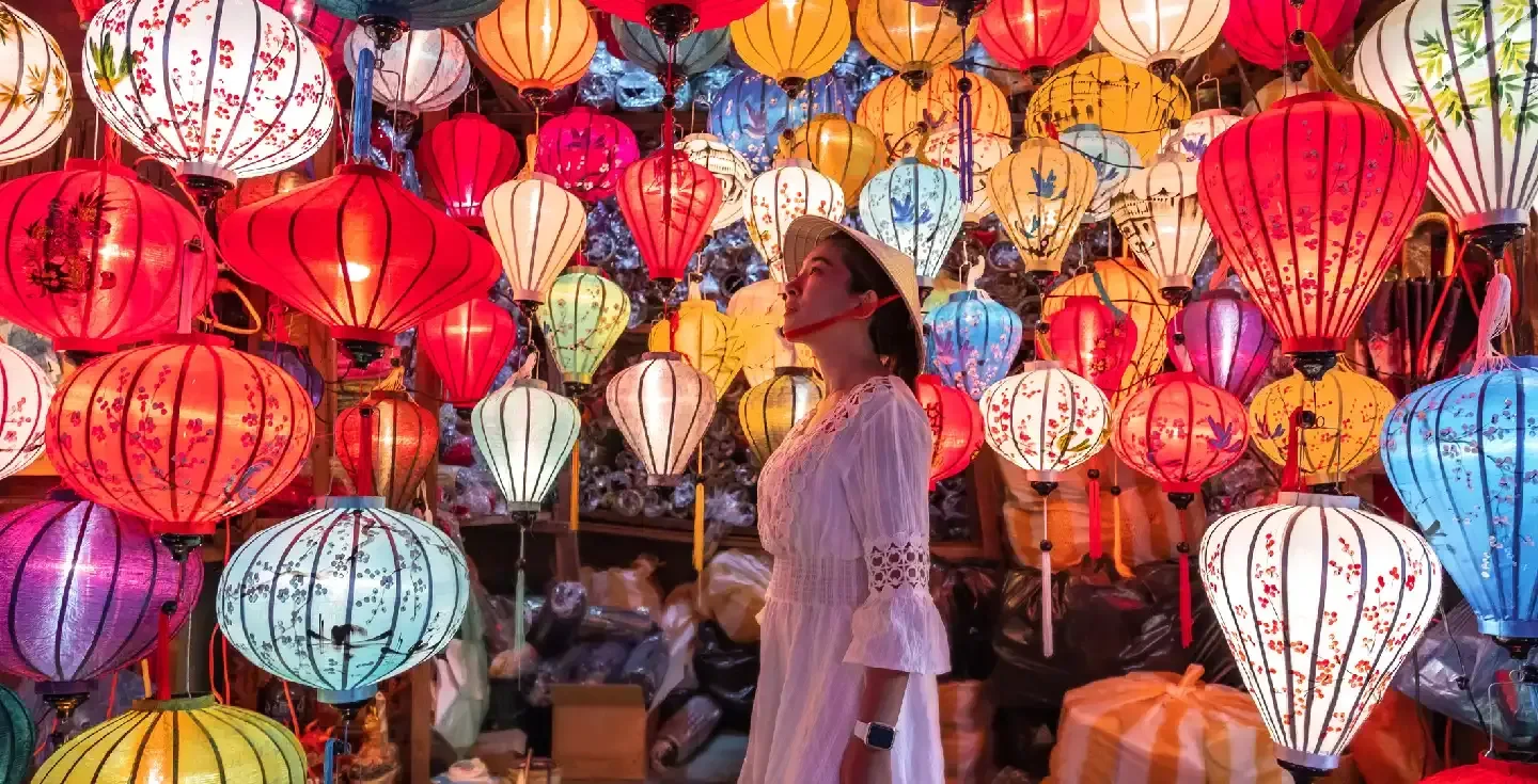 Mujer viajera eligiendo faroles en Hoi An, Vietnam.