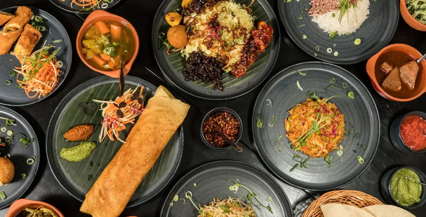 Una selección de platos de Sri Lanka, pan papadam y una dosa de pollo en el centro.