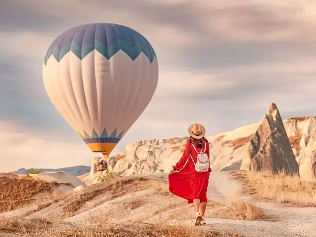 Mujer admirando globos aerostáticos al amanecer en Capadocia 