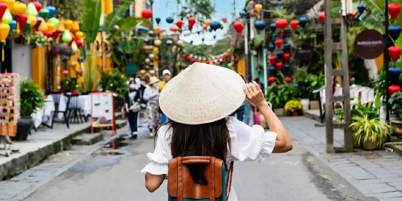 A tourist woman in a Non La enjoys exploring Hoi An’s Old Town in Vietnam.