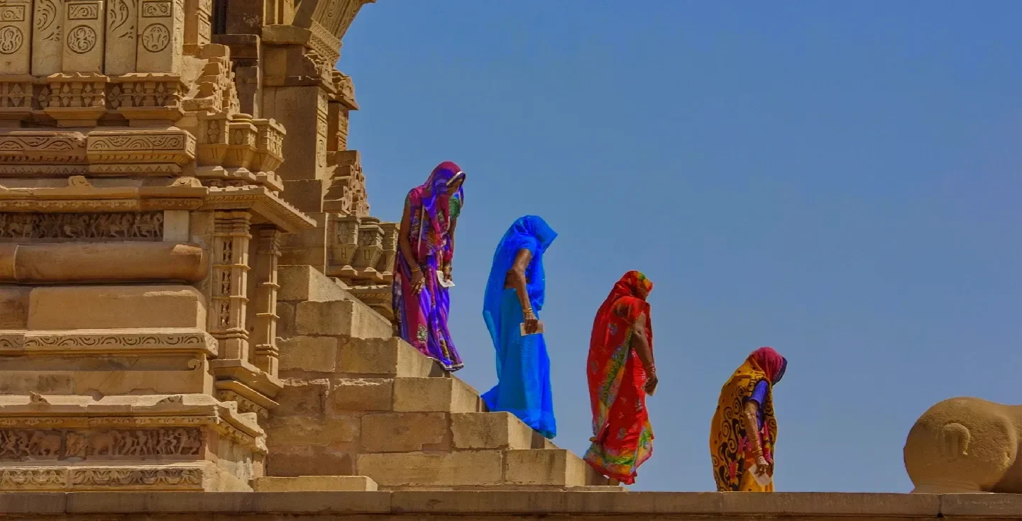 Cuatro mujeres indias, vestidas con saris tradicionales multicolores.