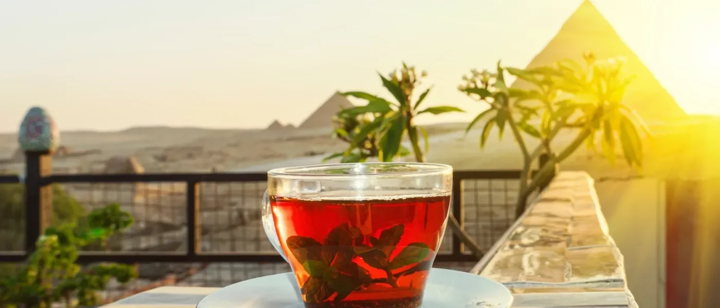 Tè alla menta in primo piano con vista panoramica sulle Piramidi di Giza.