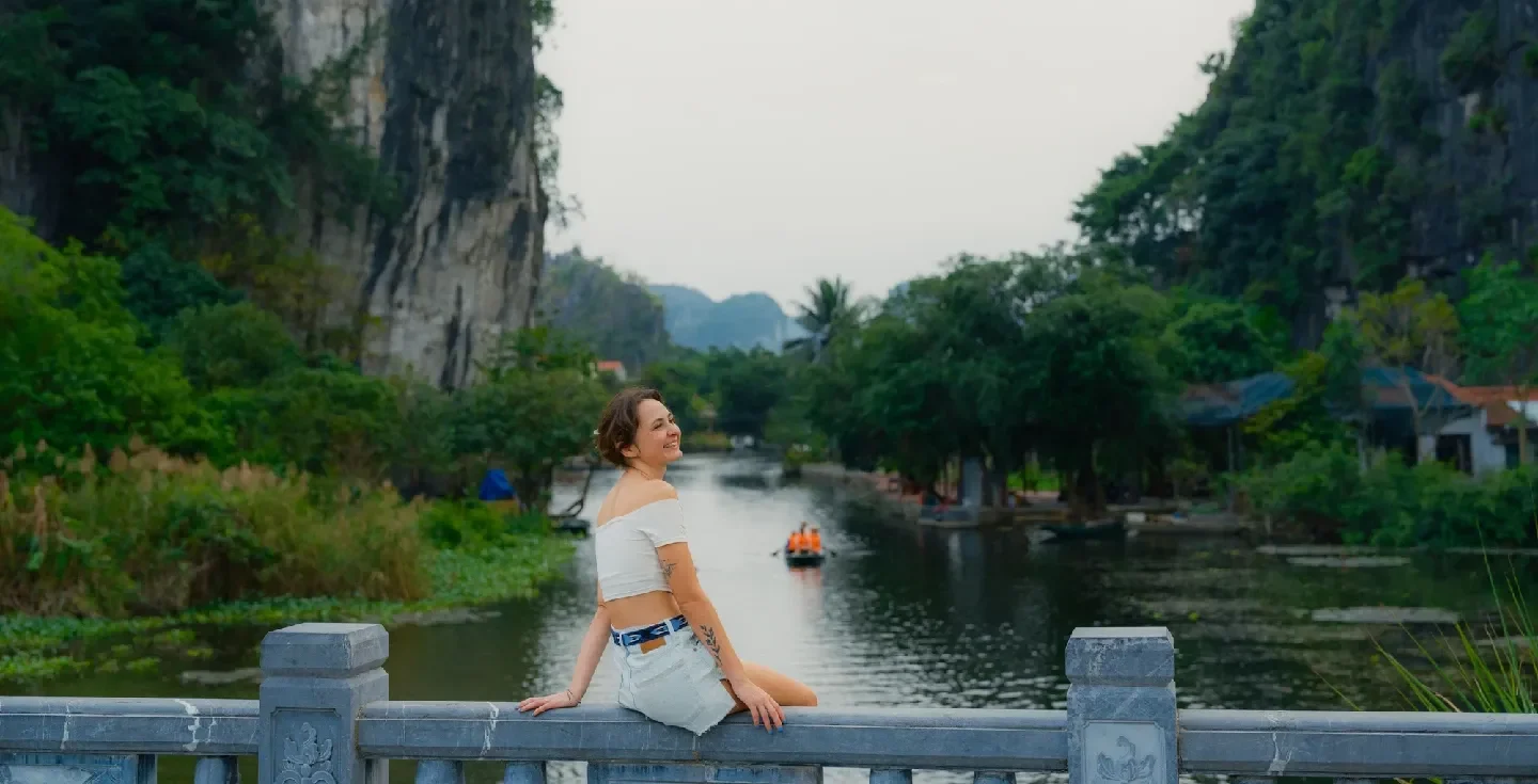 Mujer contemplando un pintoresco río rodeado de montañas kársticas en Trang An durante un viaje al norte de Vietnam.