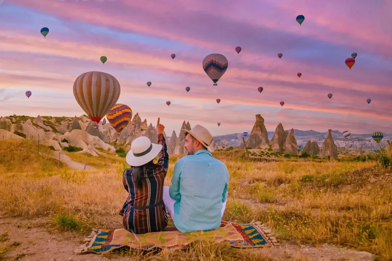 A couple watching hot air balloons rise over Cappadocia.
