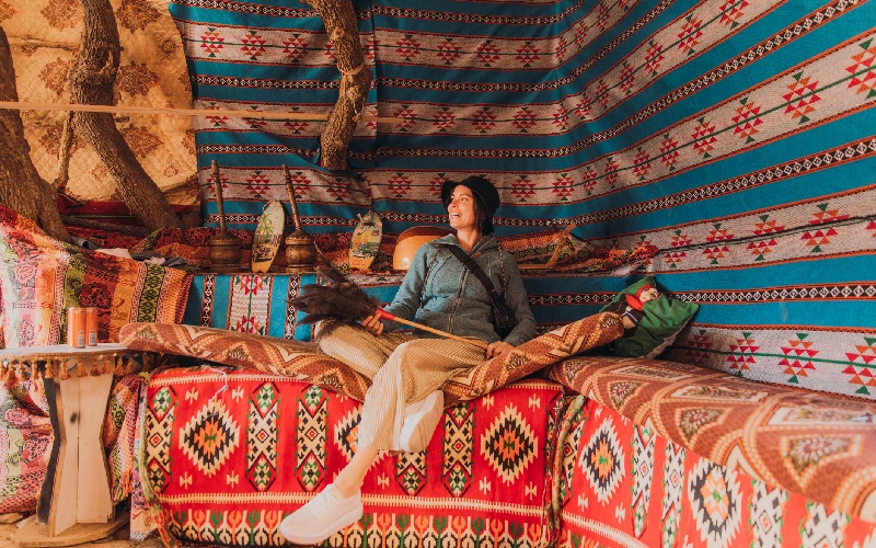 Happy female traveler relaxing at the colorful bedouin camp in Petra, Jordan