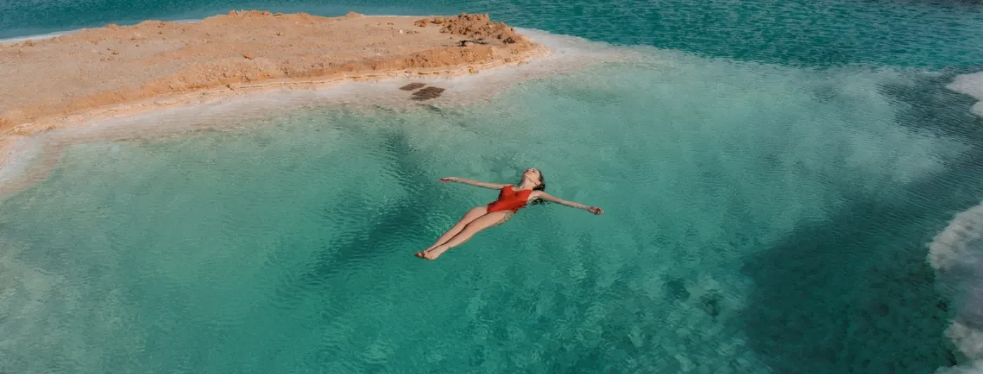 Giovane donna che nuota in un lago salato nell'oasi di Siwa