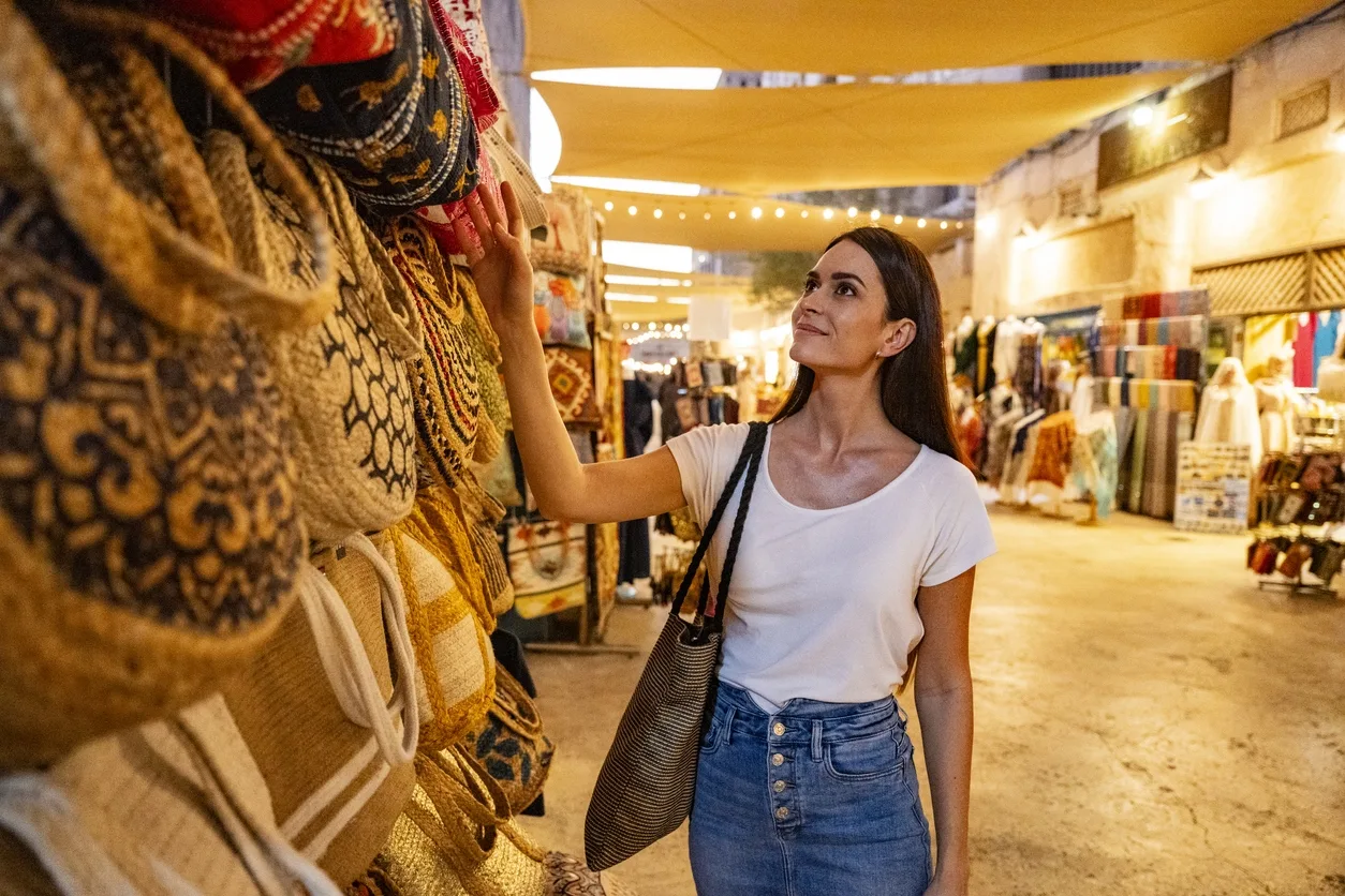 Mid adult female tourist looking at bags in Dubai souk