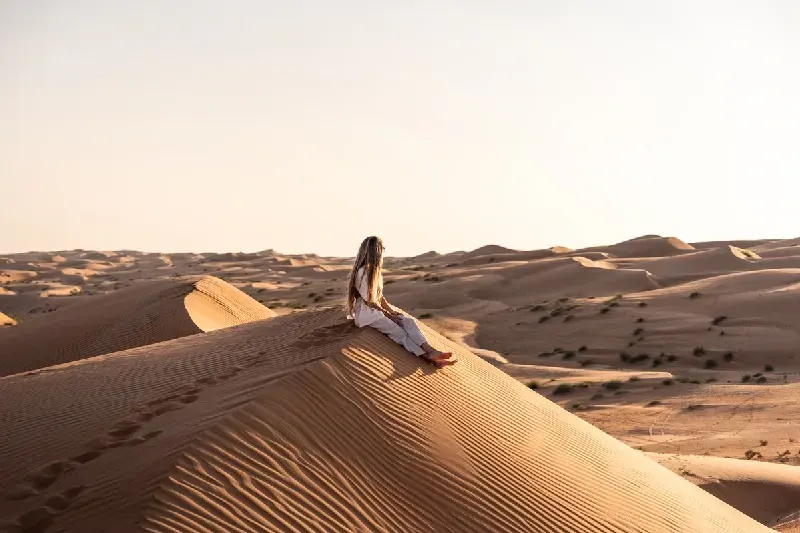Woman relaxing on desert sand dune in oman