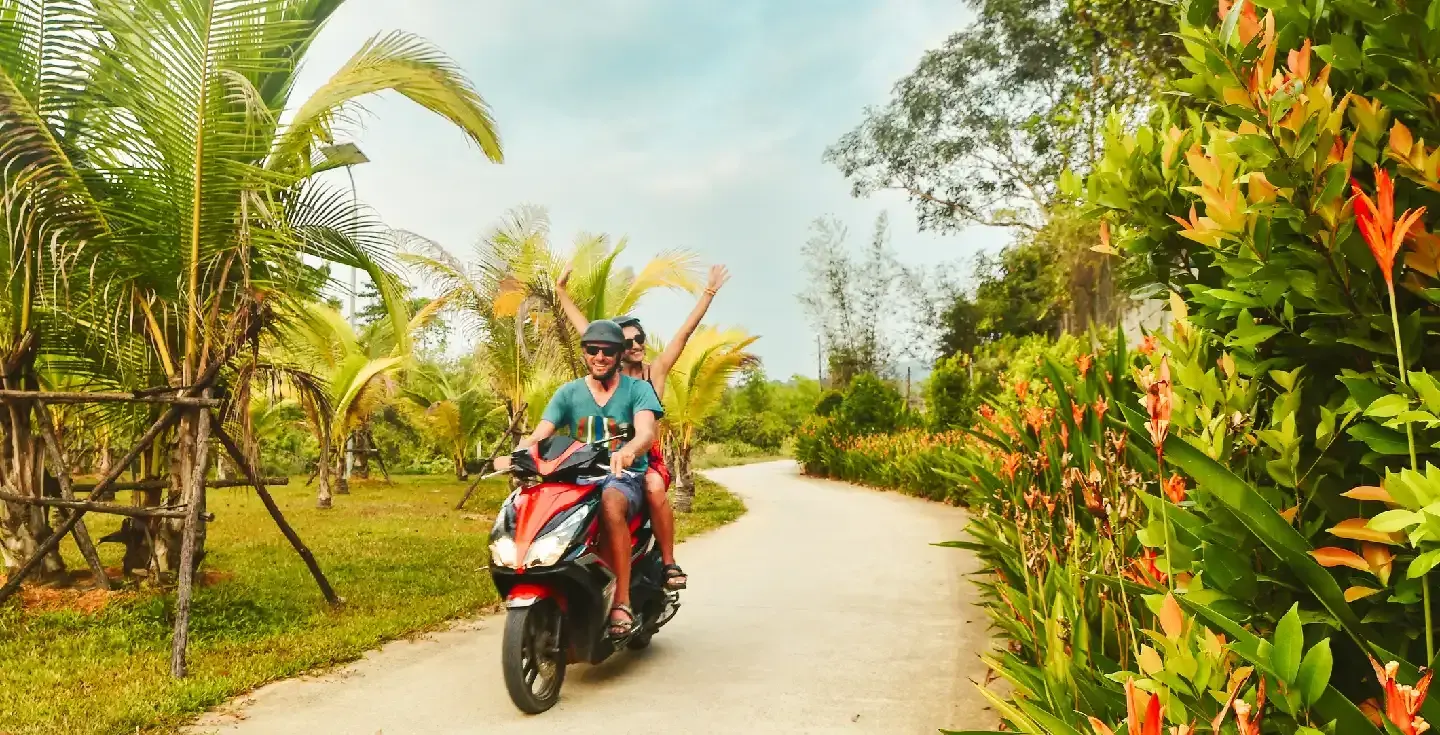 Pareja feliz y sonriente viajando en moto scooter con cascos de seguridad en la isla de Phu Quoc, Vietnam.