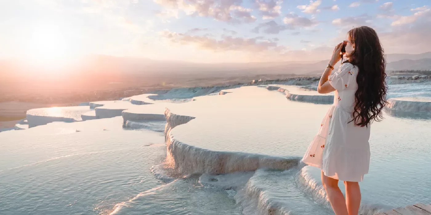 Traveler capturing sunset shots at Pamukkale’s travertine pools, natural wonders in Turkey.