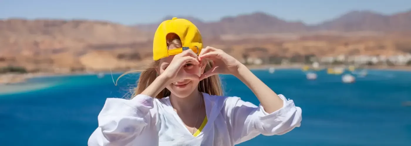 Ragazza bionda vestita di bianco che si tiene per mano a formare un cuore