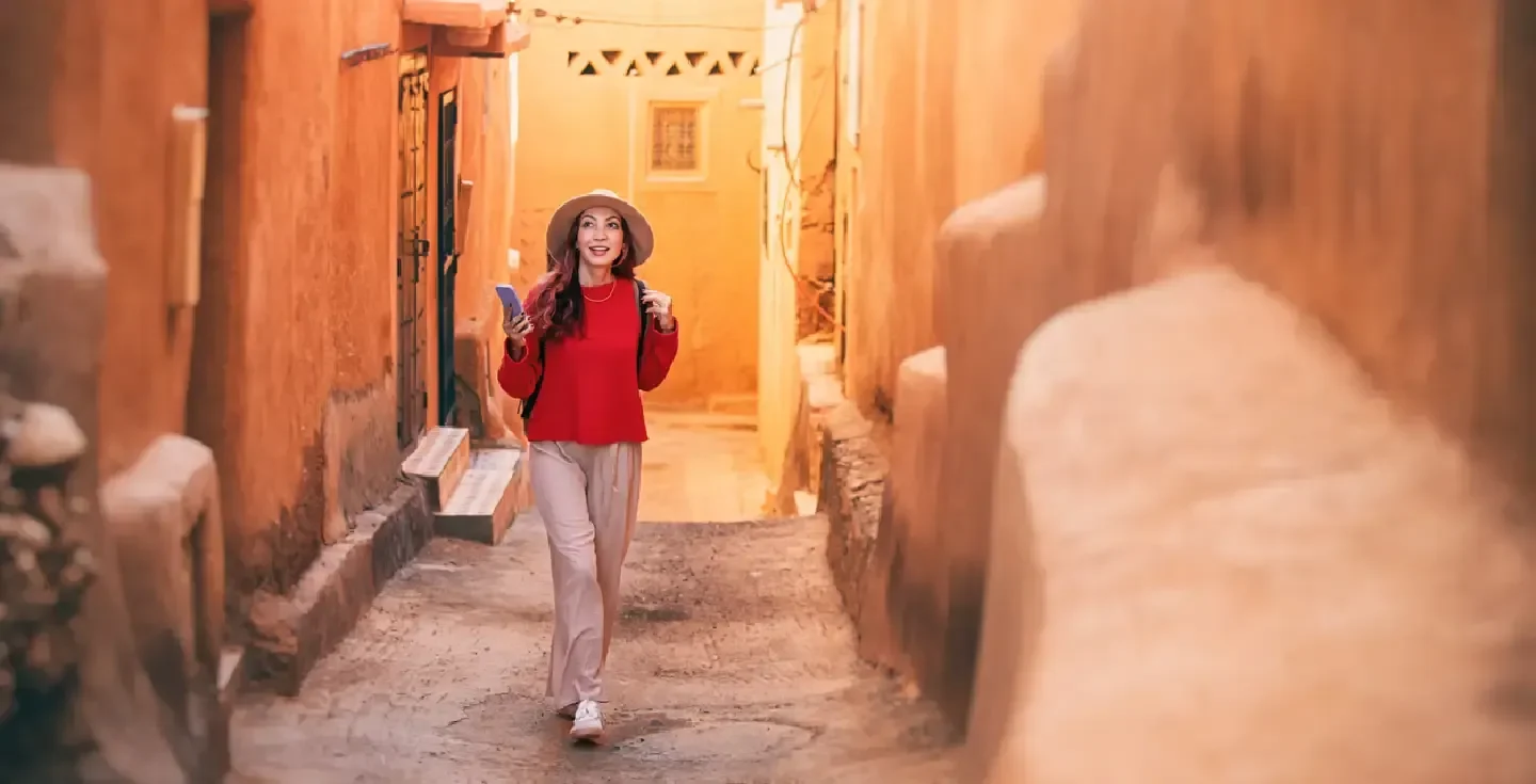 Joven turista con mochila y sombrero caminando por una estrecha calle de Ait Ben Haddou, Marruecos