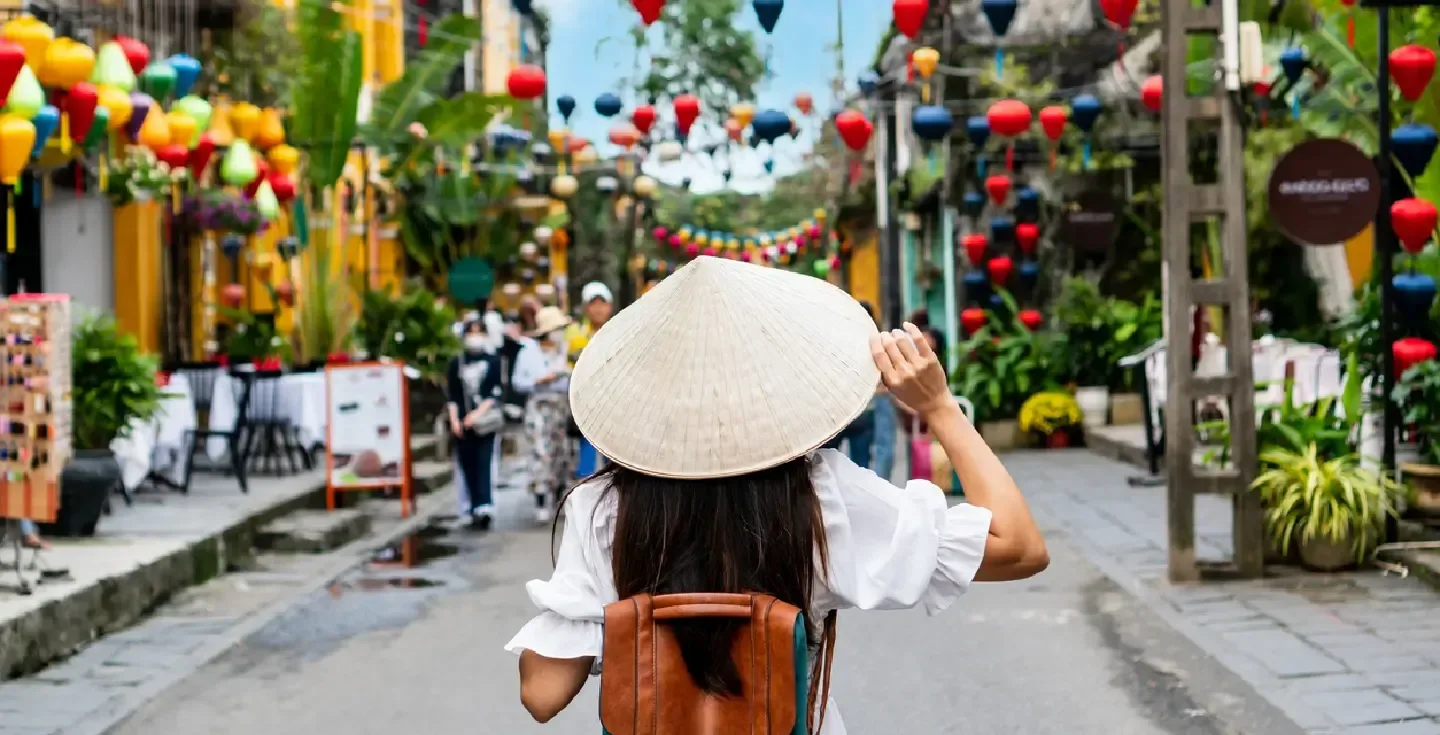 Mujer turista asiática despreocupada usando un non la (sombrero tradicional vietnamita) disfrutando de las vistas en Hoi An.