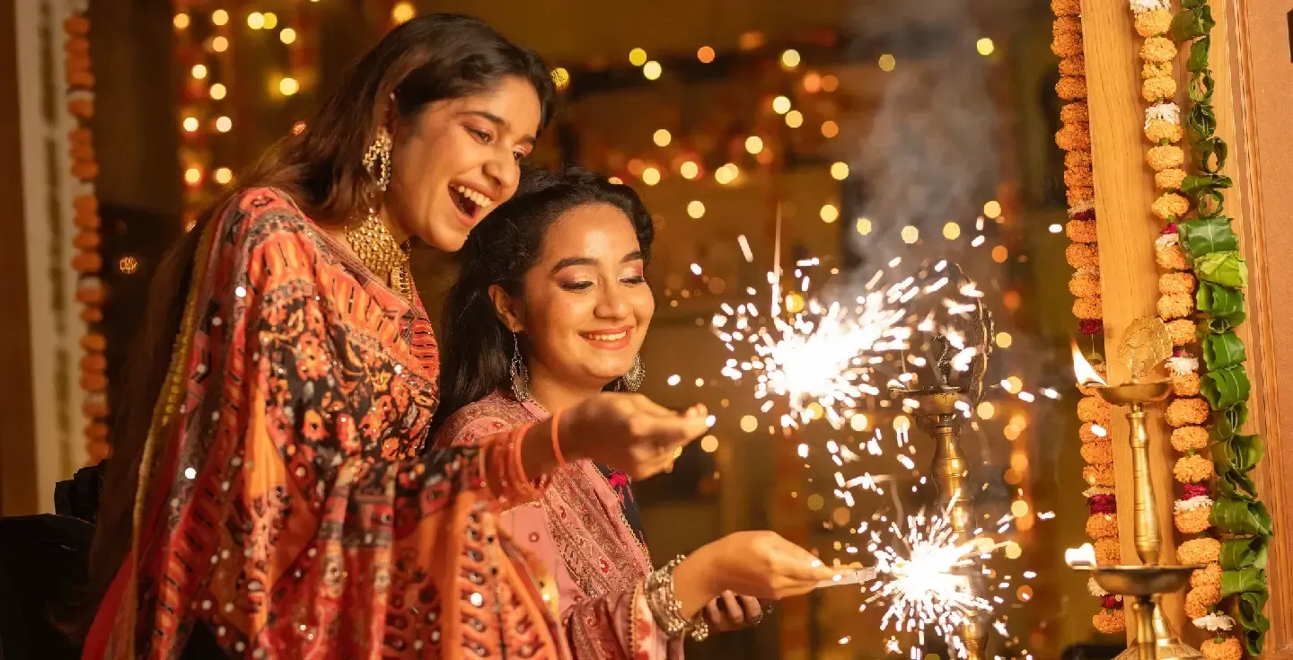 Dos hermanas juegan con bengalas mientras celebran juntas el festival de Diwali.