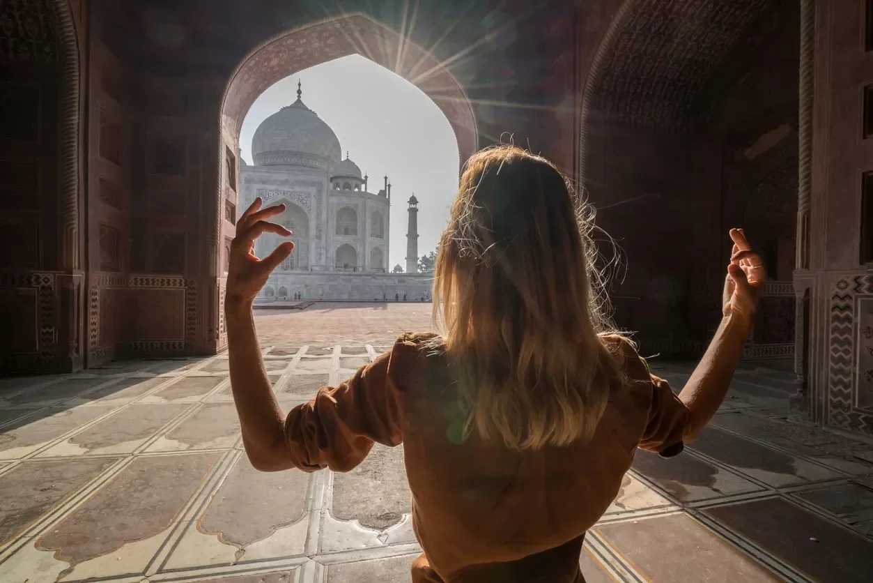 Young woman practicing yoga in India at the famous Taj Mahal