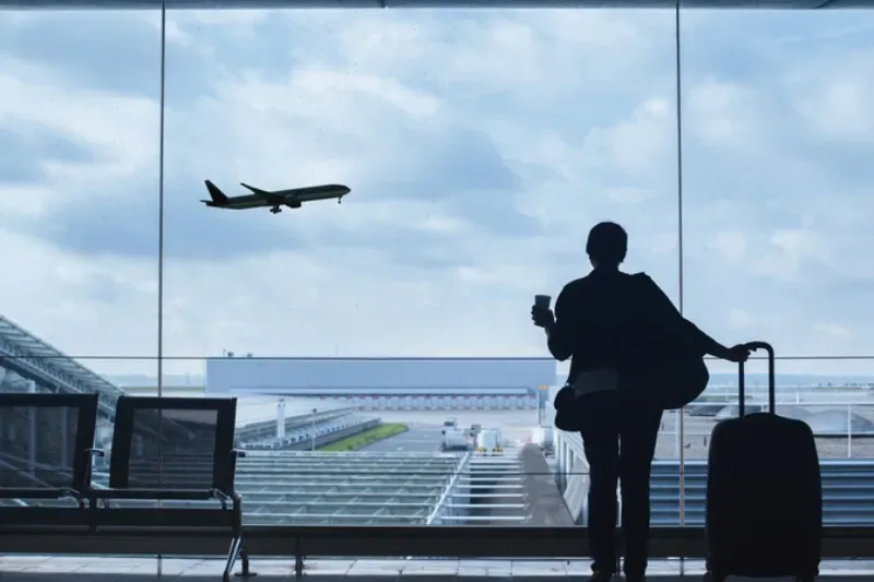 Reisender am Flughafen schaut sich das abhebende Flugzeug an