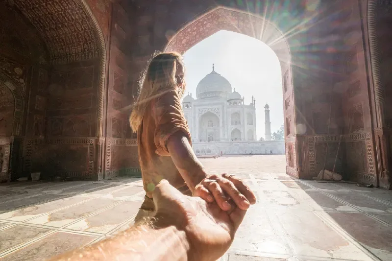 Female tourist leading her partner to the Taj Mahal in Agra.