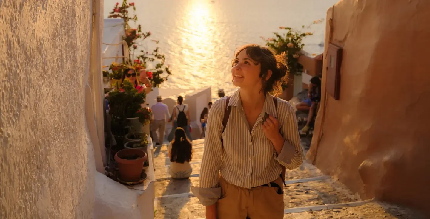 Mujer caminando por las calles de la isla de Santorini al atardecer.