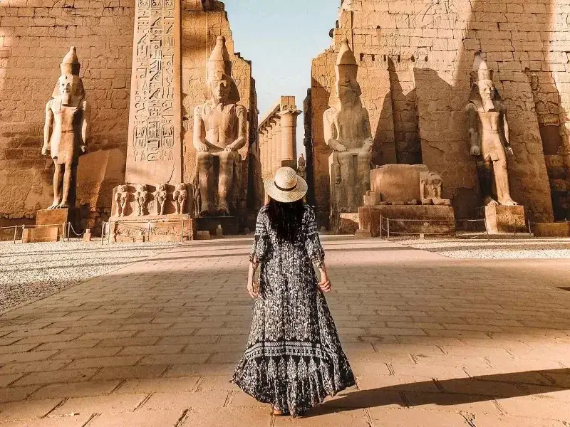 a tourist lady in white and black dress stands in ancient temple