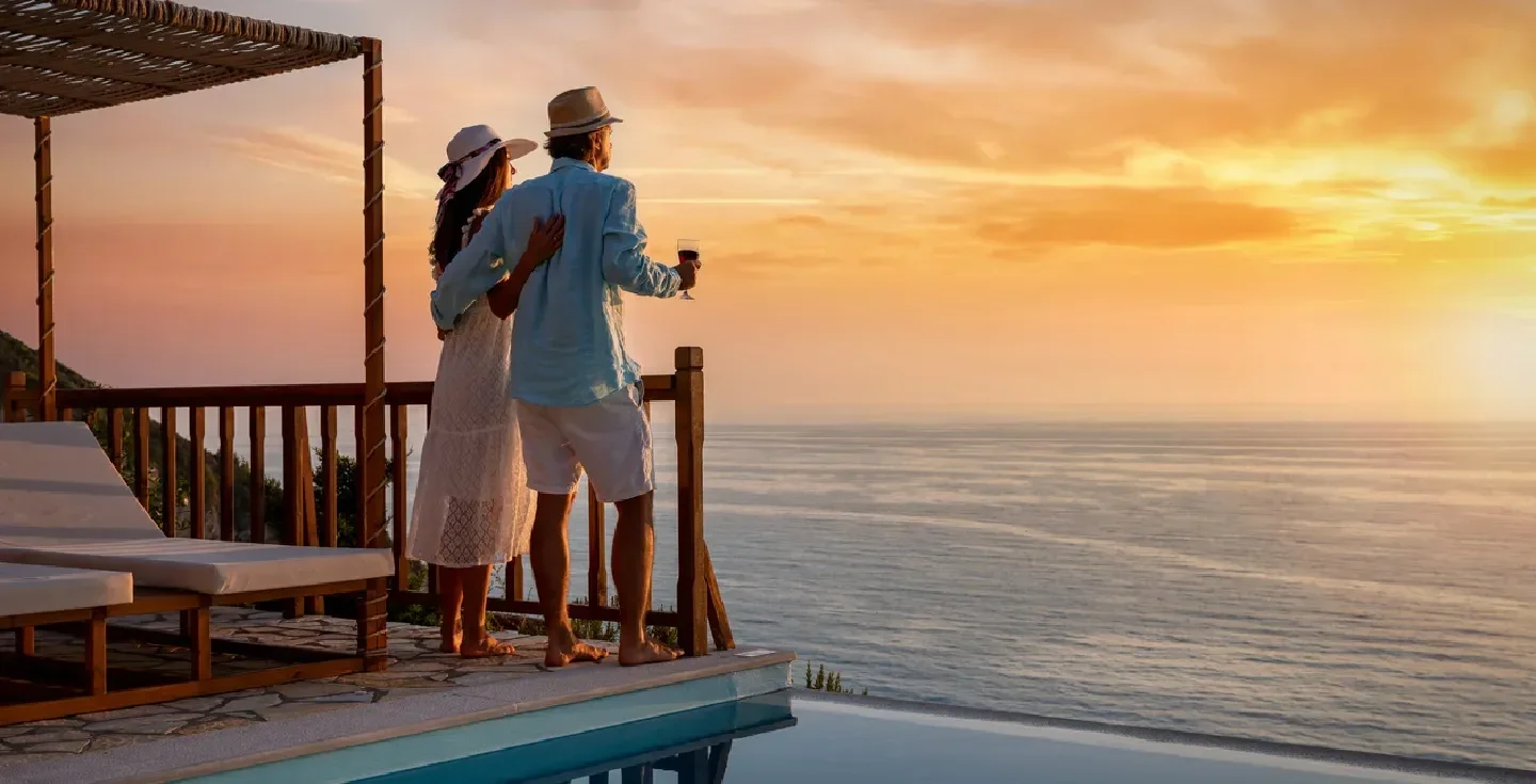 Una pareja romántica de vacaciones de verano disfruta del atardecer sobre el mar Mediterráneo junto a la piscina.