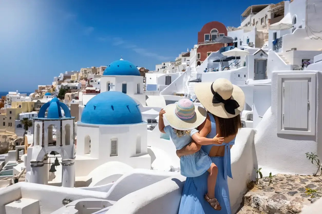 A tourist mother and her daughter looking at the whitewashed houses of the village Oia 