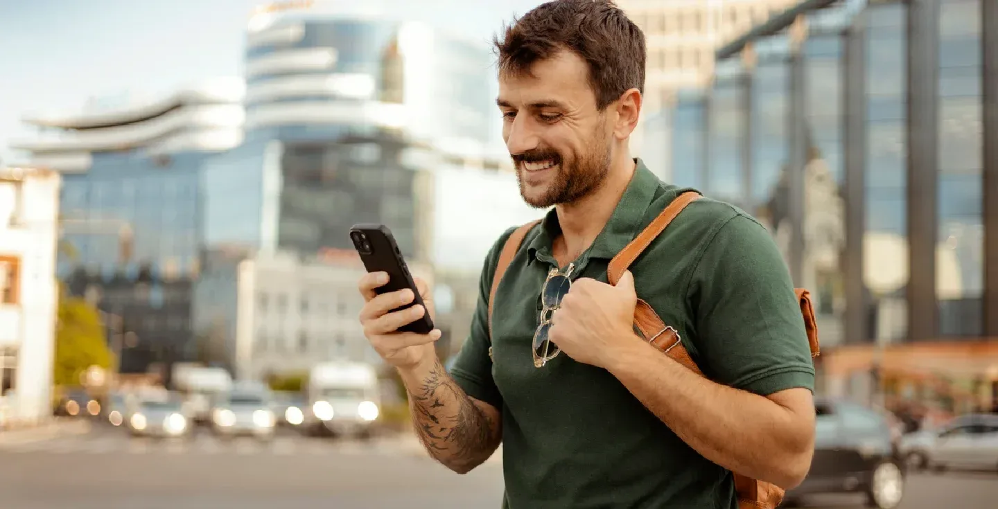 hombre-hipster-con-barba-y-estilo-moderno-usando-un-smartphone-en-la-ciudad-sobre-un-fondo-urbano