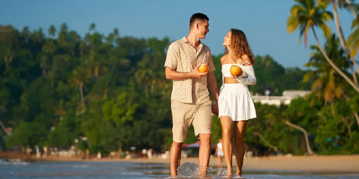 Romantic couple walking on a sunny tropical beach in Sri Lanka.