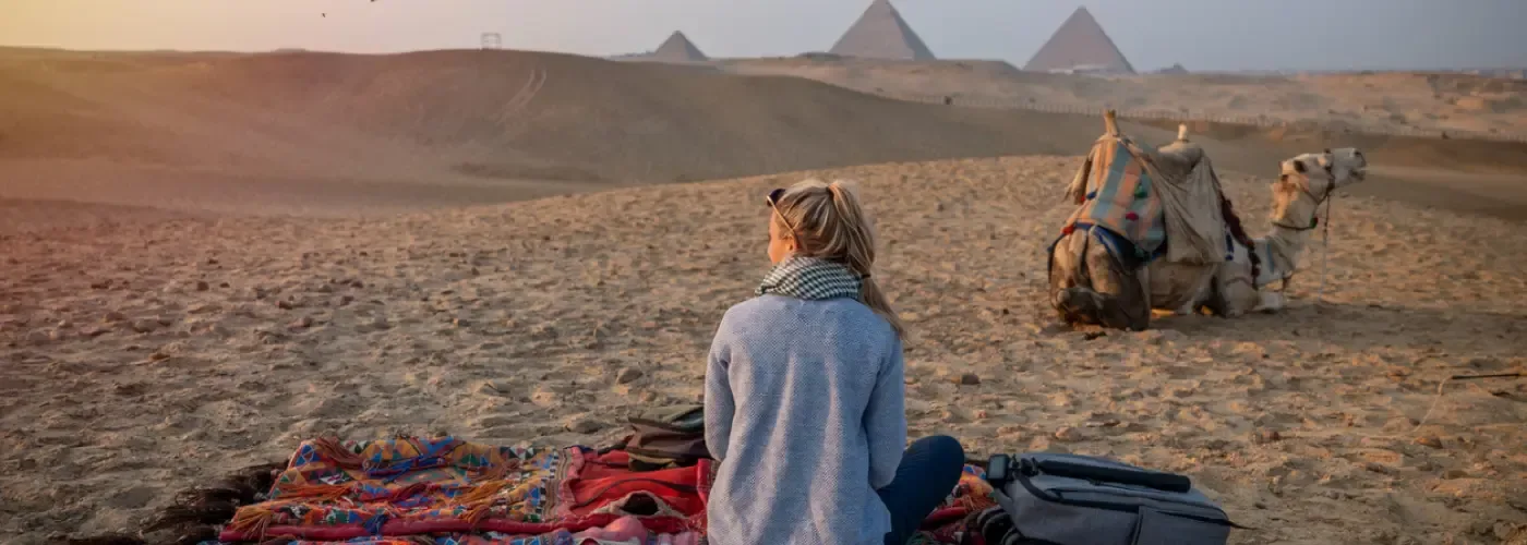 Vista posteriore di una turista che si gode la visita alle Piramidi di Giza, in Egitto.