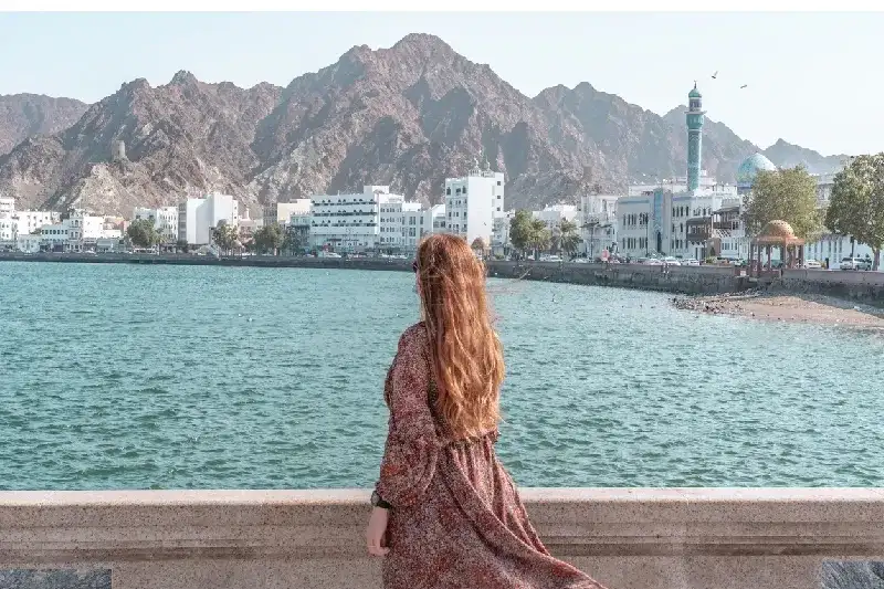 A woman gazes over Muscat’s coastline, reflecting Omani beauty and serenity.
