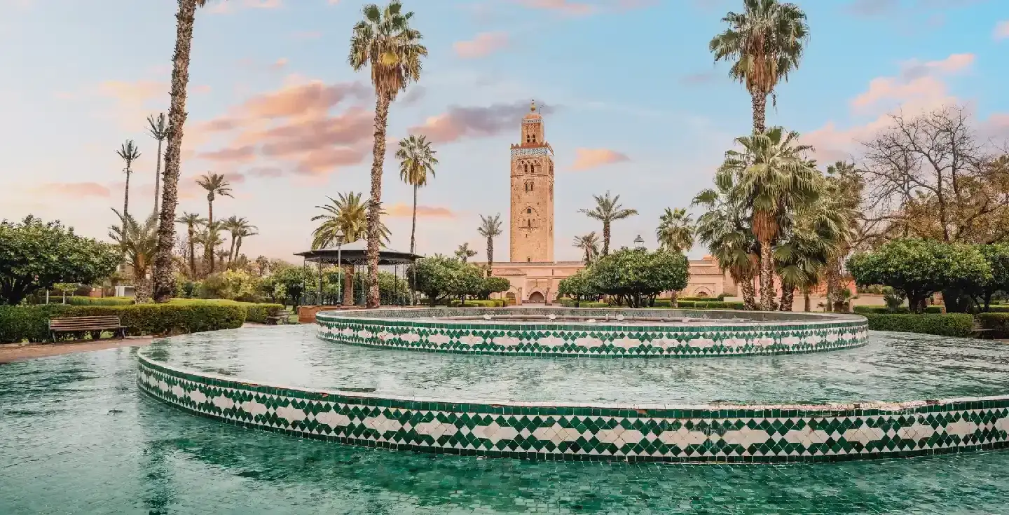 La majestuosa Mezquita Koutoubia se eleva sobre una fuente serena en Marrakech, Marruecos.