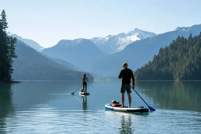 Paar paddelt gemeinsam auf SUP-Boards über einen Bergsee in Whistler