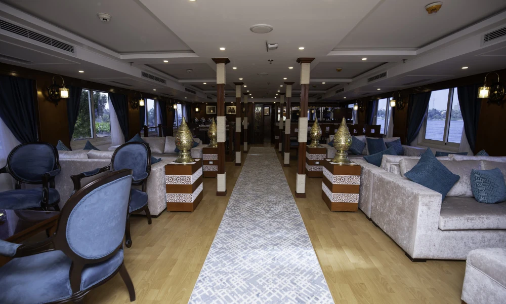 Lounge der Dahabeya Queen Isis mit Sofas, Sesseln und Panoramafenstern zum Nil