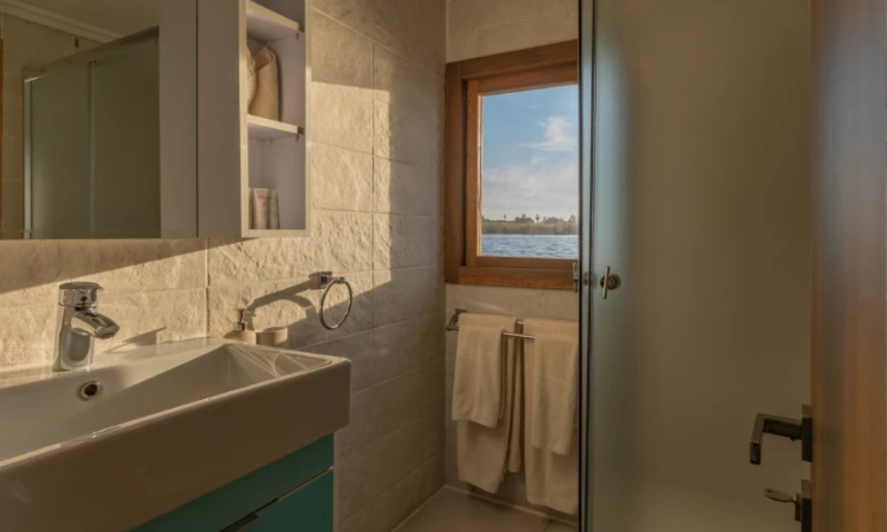 Badezimmer mit Fenster und Blick auf den Nil an Bord der Nuun & Nuut Dahabiyya