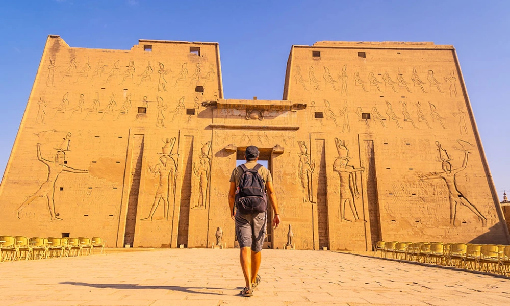 Mann mit Rucksack geht auf das Eingangstor des Edfu-Tempels in Ägypten zu
