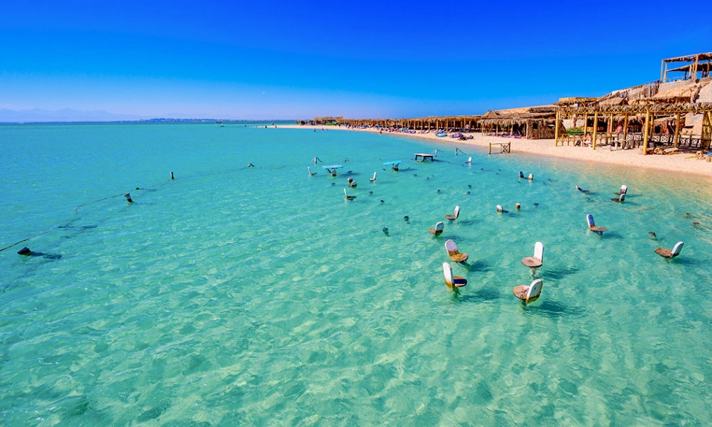 Luftaufnahme eines tropischen Strandes mit Stühlen im türkisfarbenen Wasser