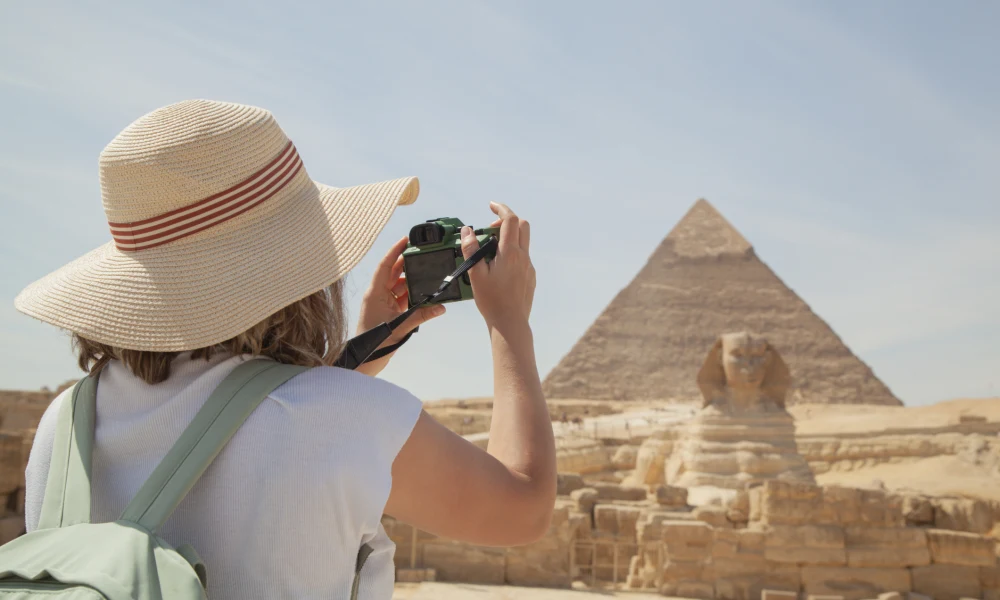 Person mit Strohhut fotografiert die Pyramiden und die Sphinx von Gizeh
