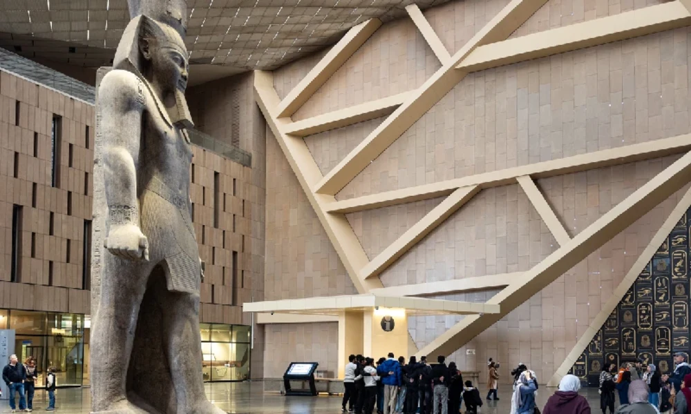 Große Pharaonenstatue in einer modernen Museumshalle mit Besuchern