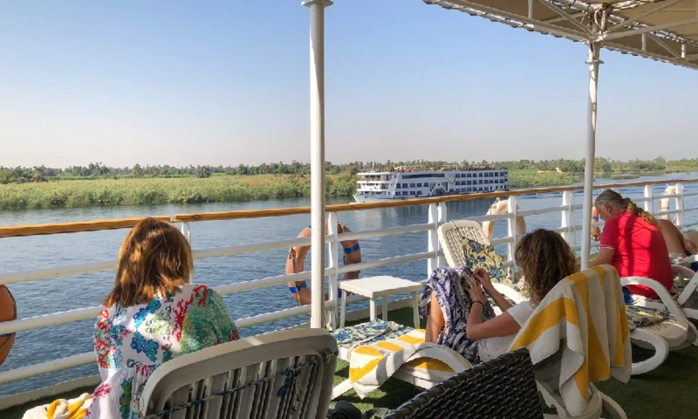Gäste auf dem Sonnendeck eines Nilschiffs mit Blick auf den Nil