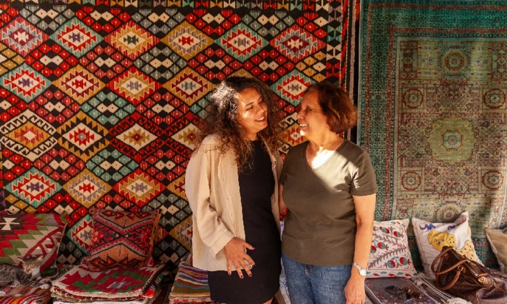 Zwei Reisende vor handgewebten Teppichen auf einem orientalischen Basar